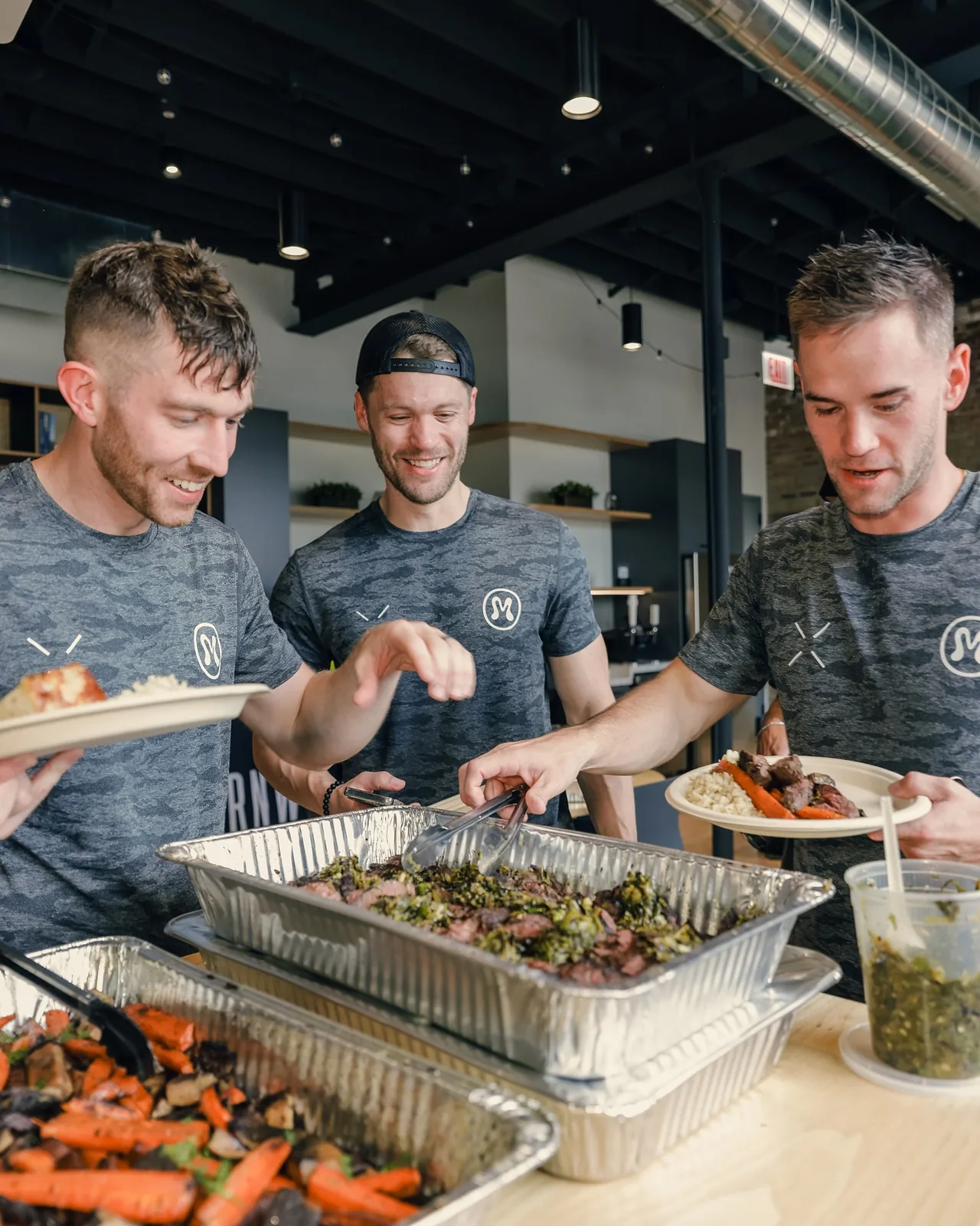 Colleagues serving themselves from a shared lunch spread in the workplace